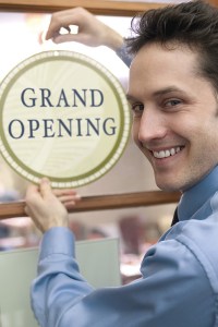 Picture of a man next to a sign that says "grand opening"